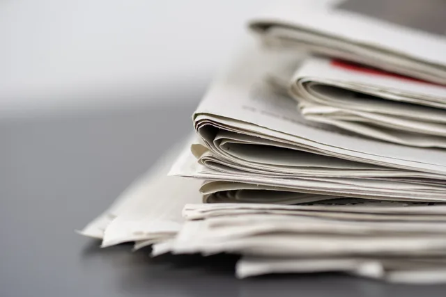 Close-up of stacked newspapers on a table, representing media and journalism. Reputation und Medienanfragen