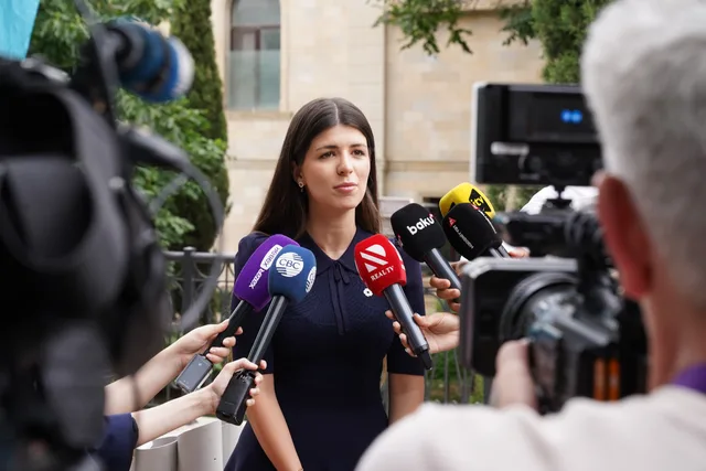 A spokesperson engages with media during an outdoor press interview surrounded by microphones. Sprecher und Freigaben eindeutig benennen